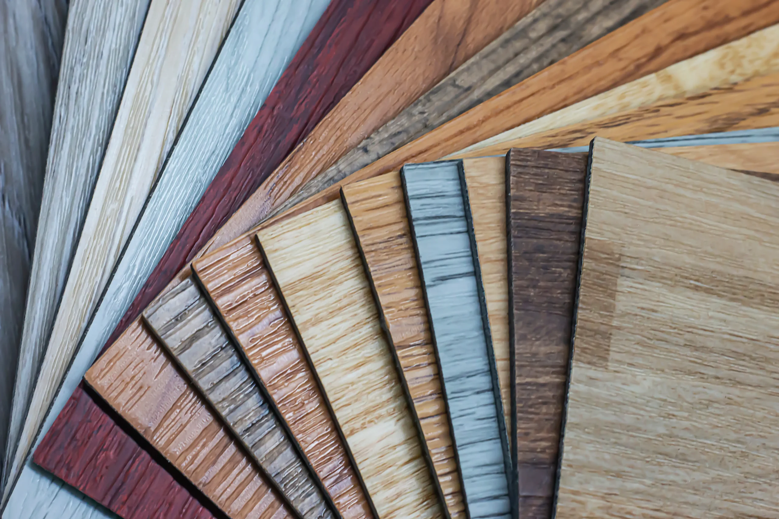 Fan display of vinyl flooring samples in multiple wood-look colors and grain patterns.